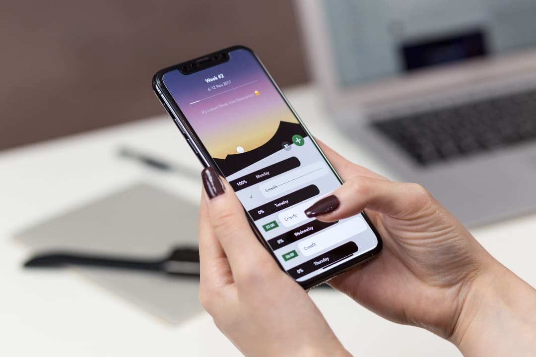 Illustrative photo of a person using a mobile app beside a laptop