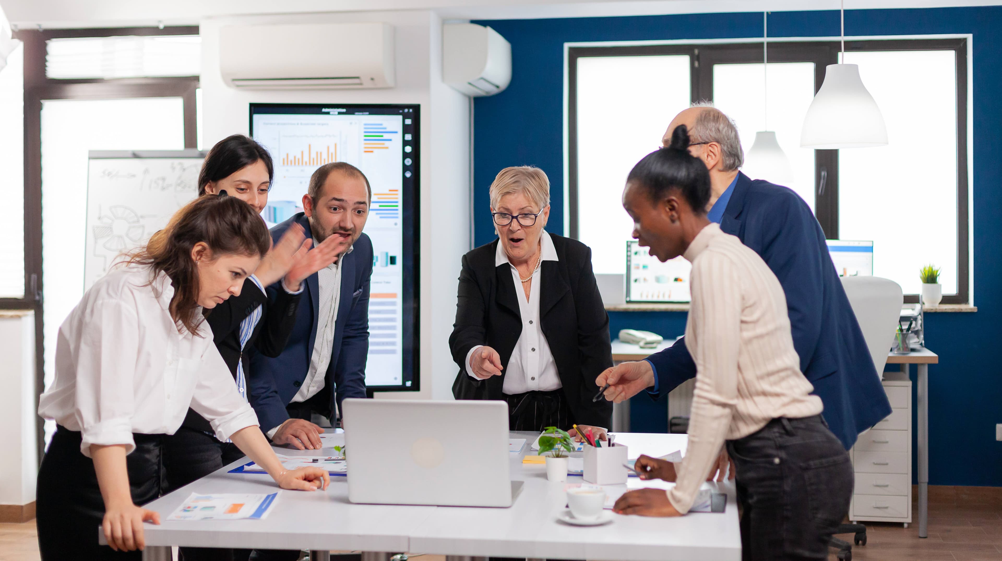 Business team collaborating around a laptop and reviewing plans in an office